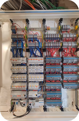 Innenansicht eines elektrischen Schaltschranks mit zahlreichen geordneten Kabeln, Sicherungen und Schaltmodulen.