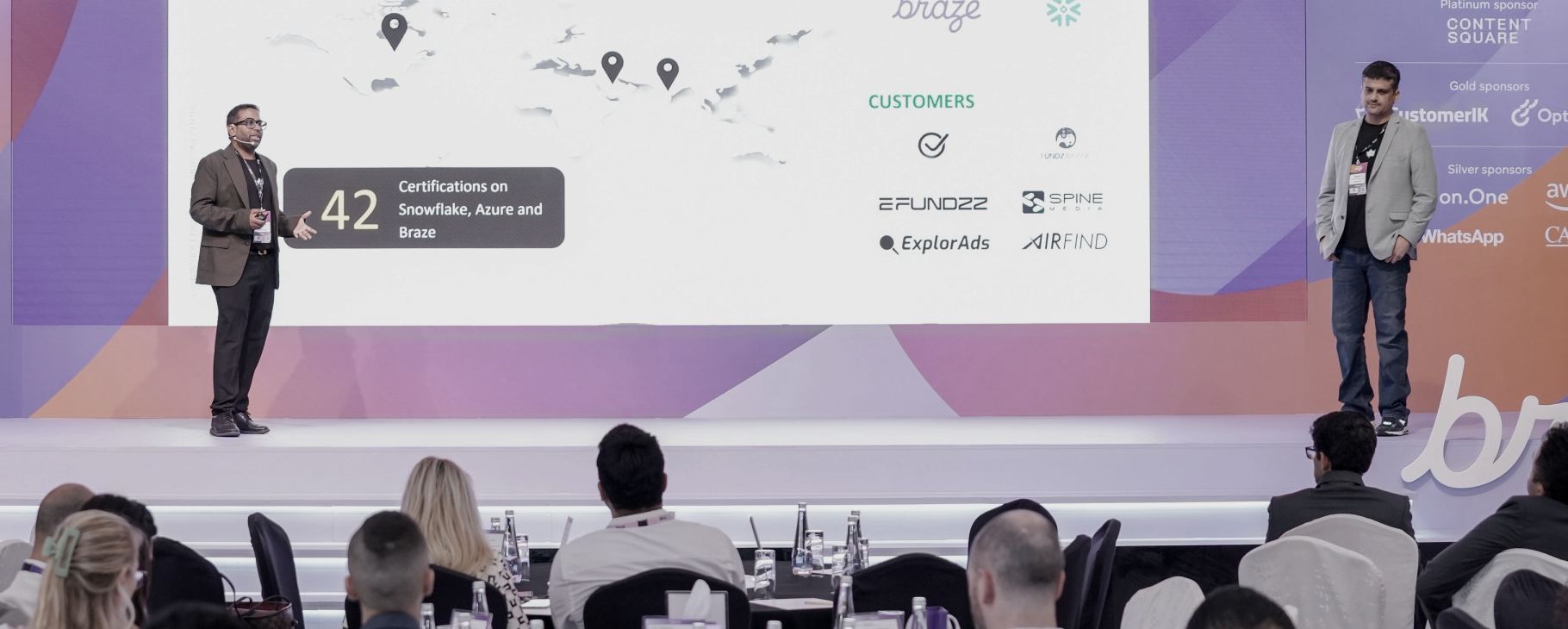 Mitra Daram and Shekhar S presenting on stage at Grow with Braze Dubai 2025, in front of a seated audience.