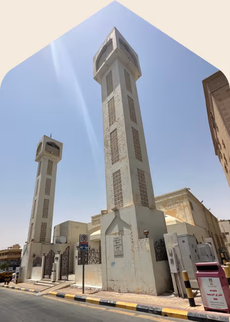 مئذنتان طويلتان من المبنى الأبيض في شارع حضري تحت سماء صافية زرقاء.
