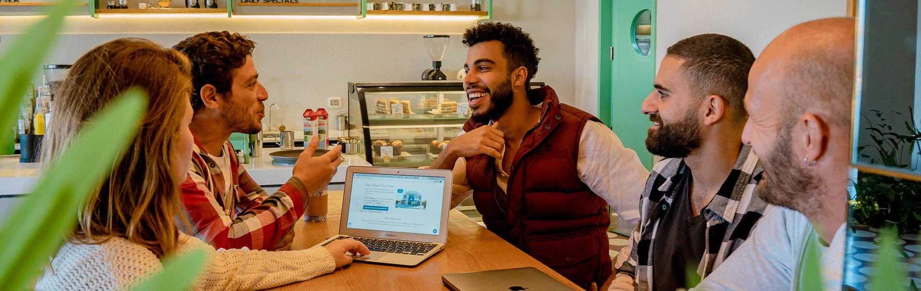 Group discussing a property decision around a laptop in a café