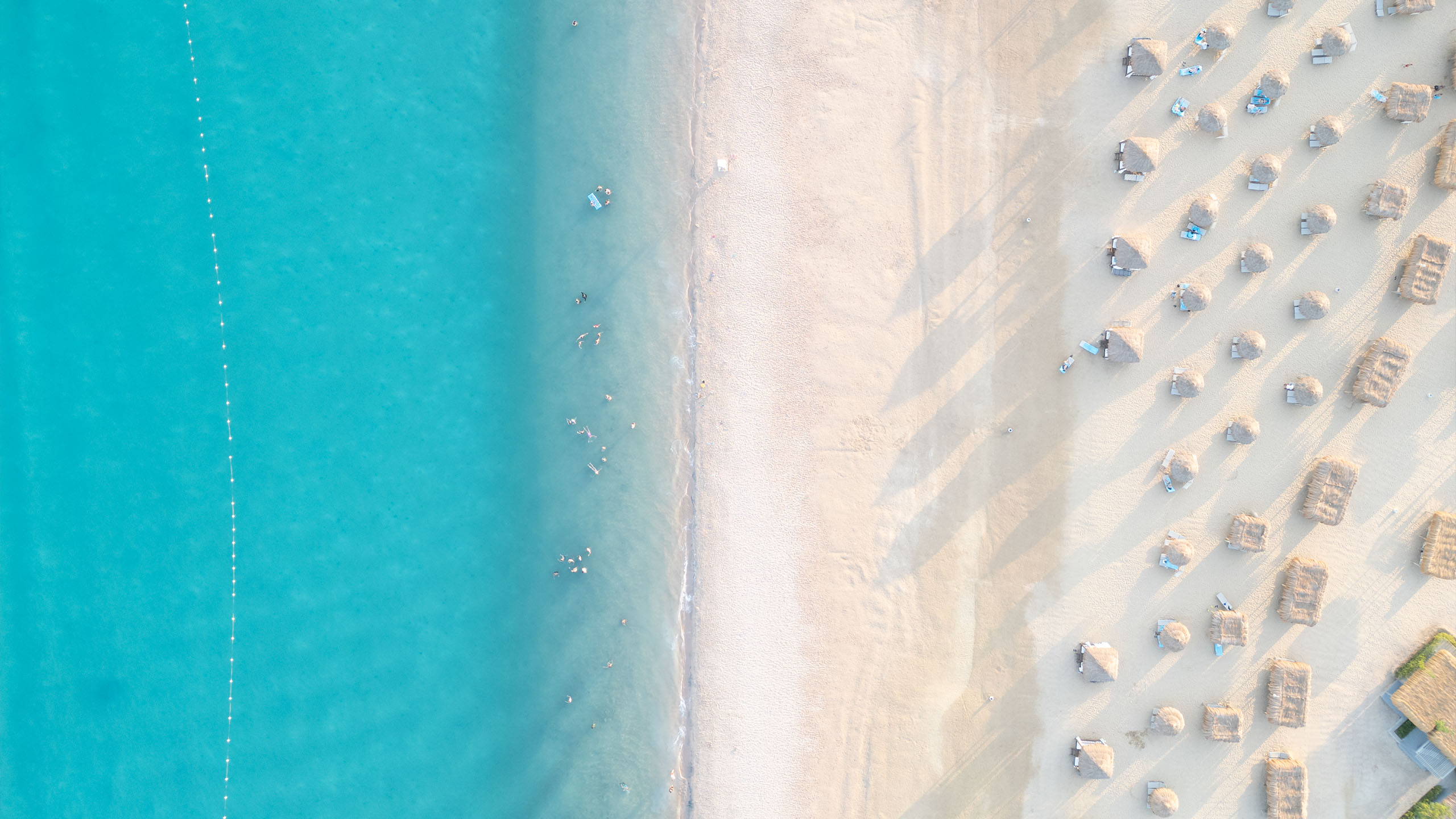 Aerial view of a Soma Bay beach with turquoise Red Sea water and thatched parasols