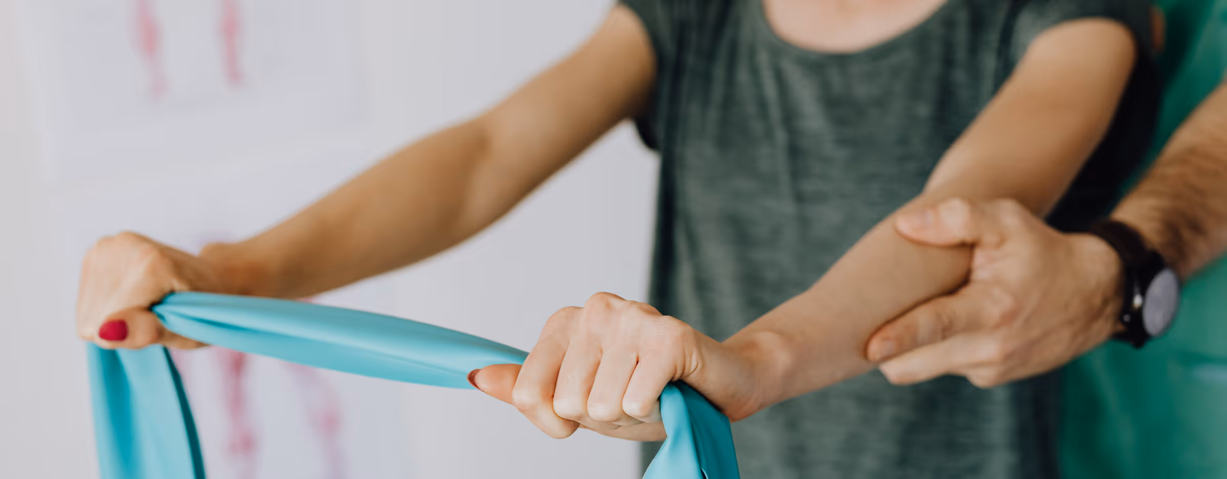 Die Hände einer Frau ziehen ein Band mit Kraft auseinander, während ihr Trainer sie unterstützt.
