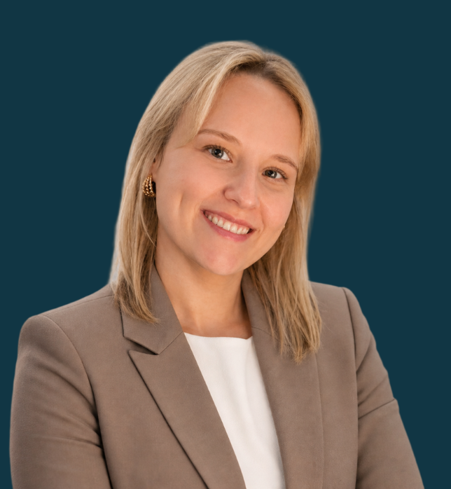 Frau mit blonden Haaren und beigen Blazer vor dunklen Hintergrund