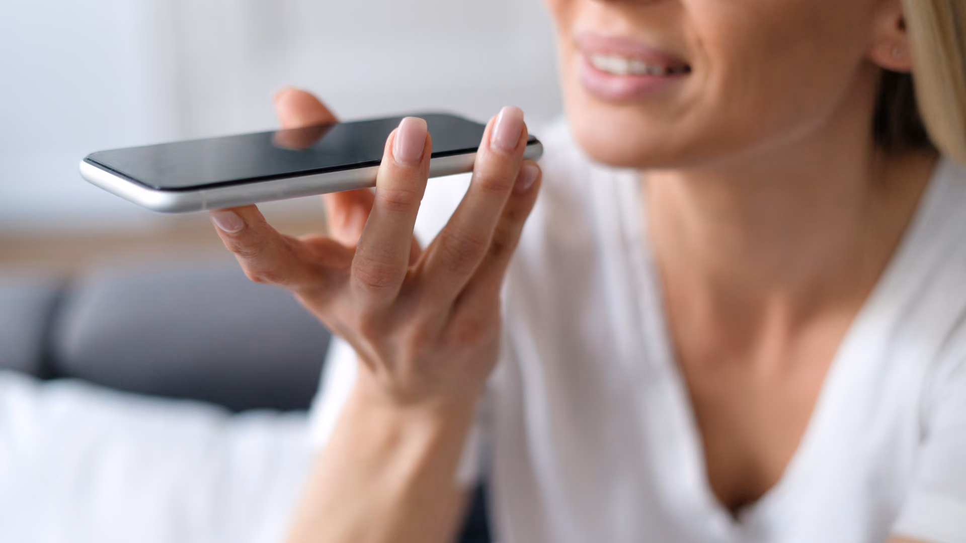 Frau hält Smartphone nah an den Mund und spricht