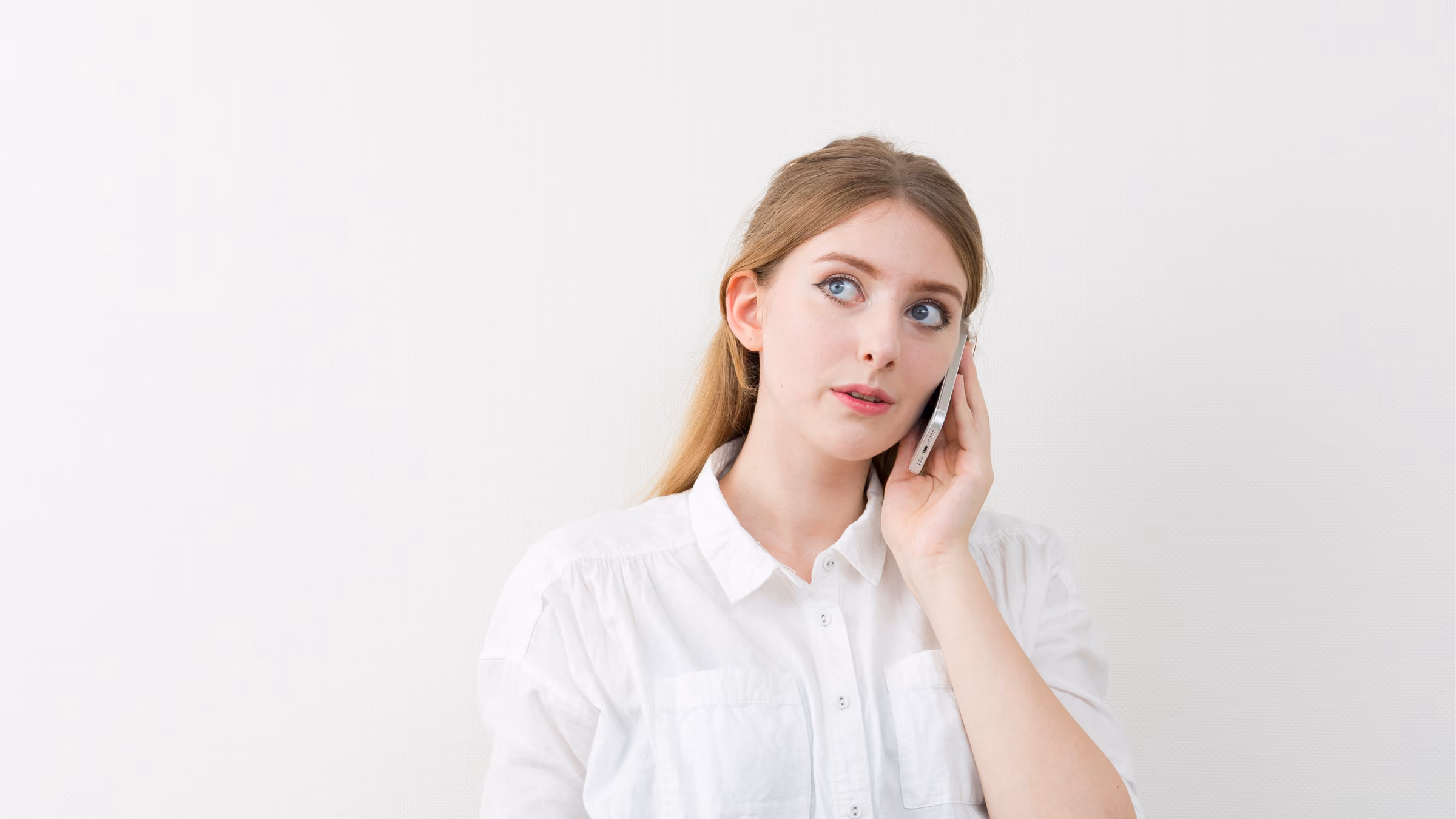 Frau in weißer Bluse telefoniert mit einem Handy.
