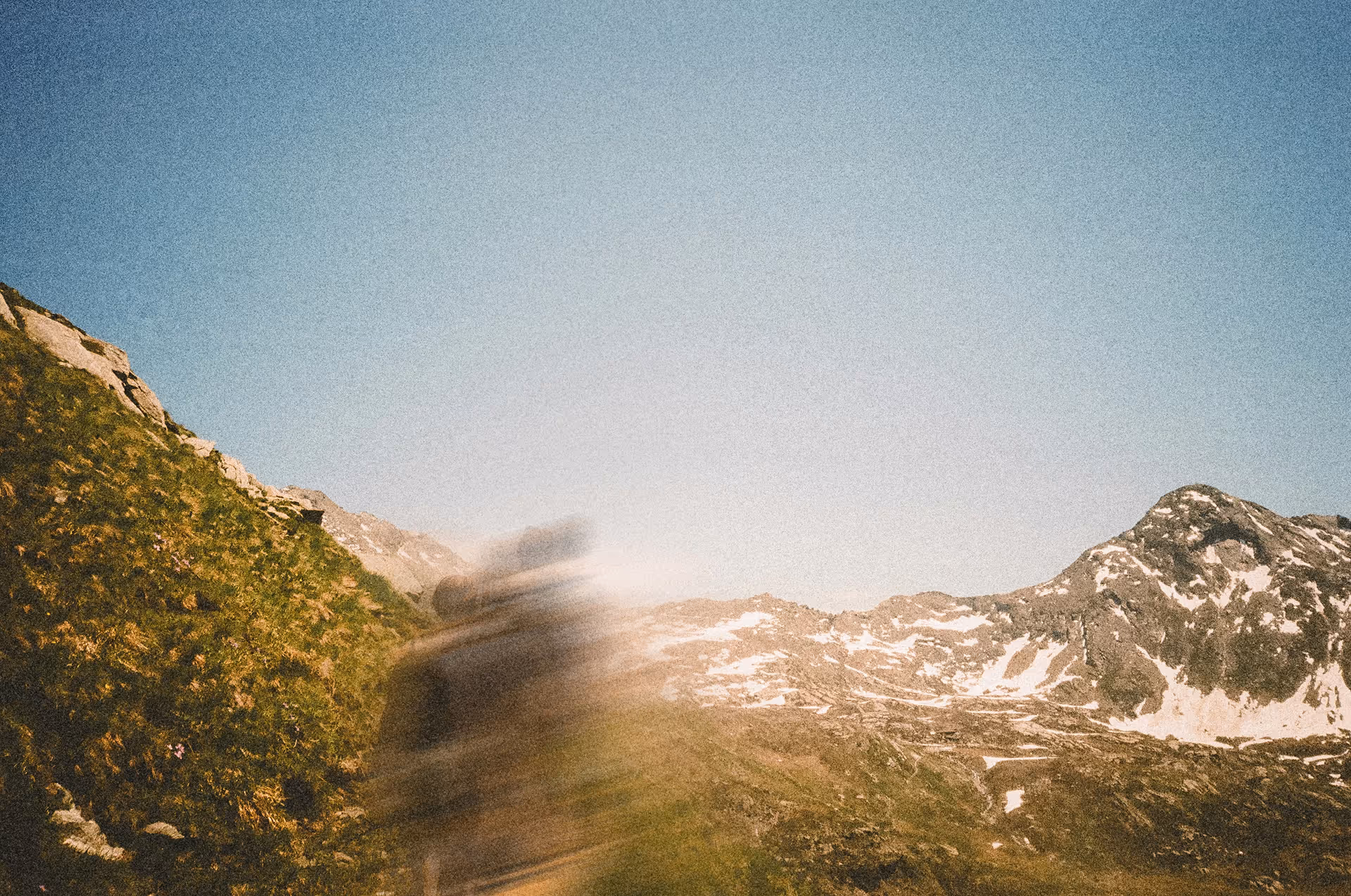 A person hiking a mountain range. Motion blur is creating an interesting effect on the person