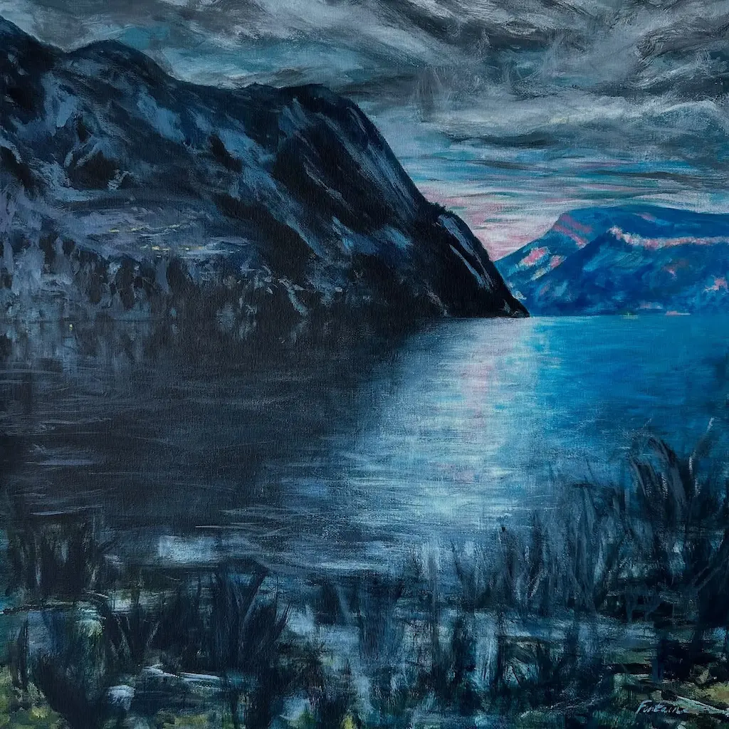 Paysage de montagnes sombres avec un lac calme sous un ciel nuageux au crépuscule.