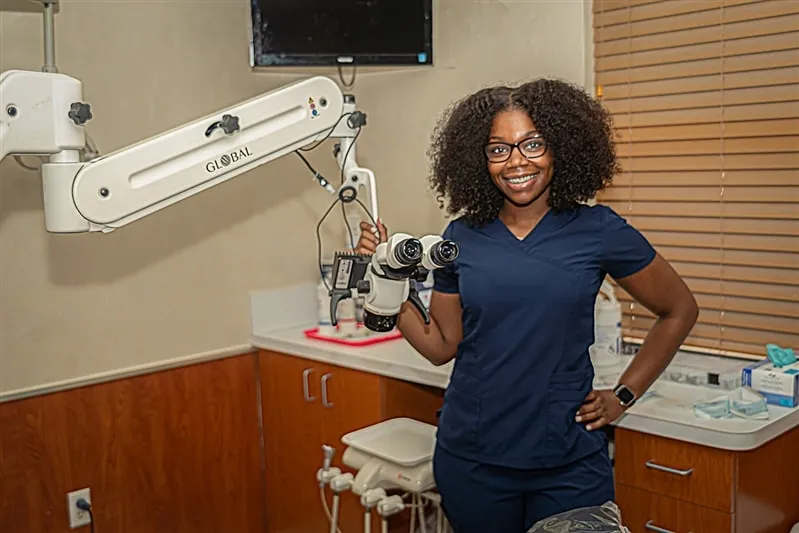 A woman in a dentist's office holding a camera.