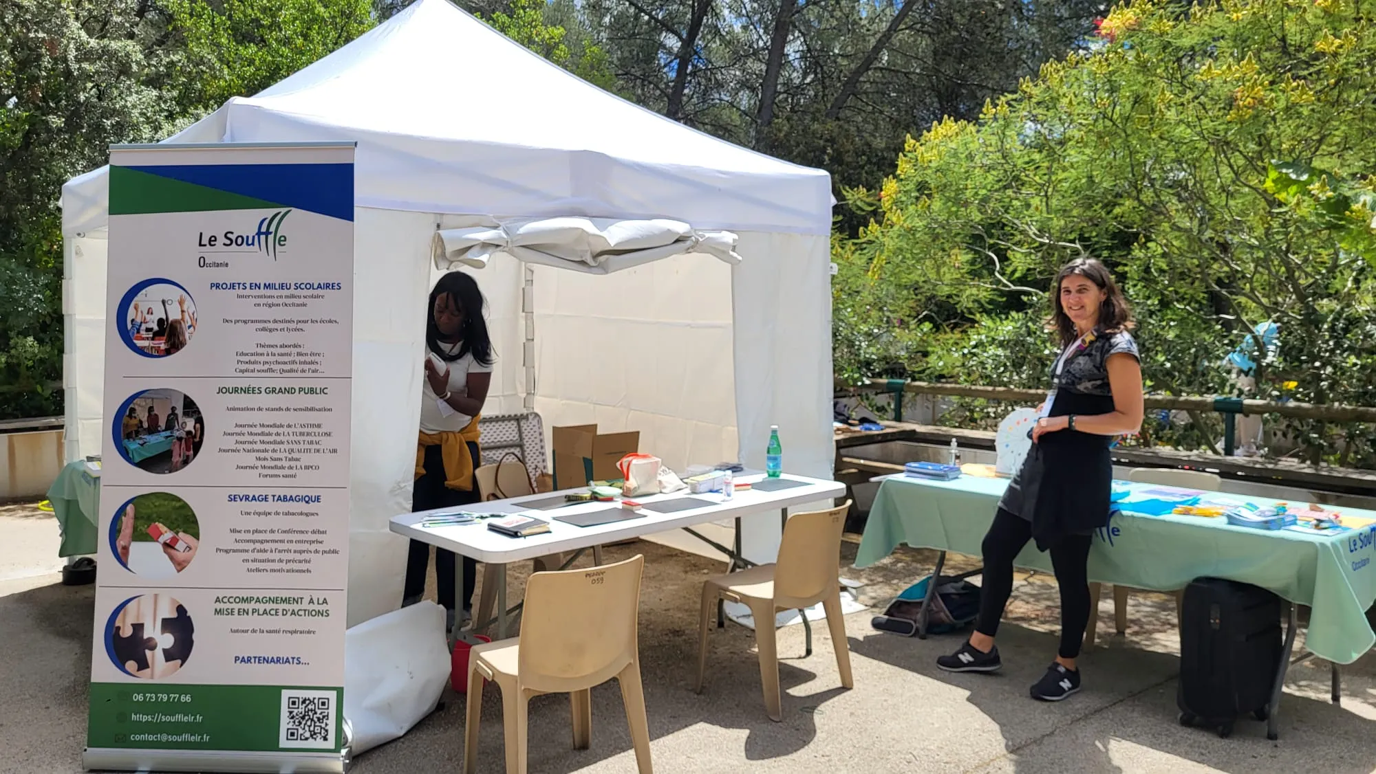 Action de sensibilisation du CNMR, comité national contre les maladies respiratoires, en France. Deux femmes à un stand d'informations en plein air avec une tente blanche et affiches sur la santé respiratoire.