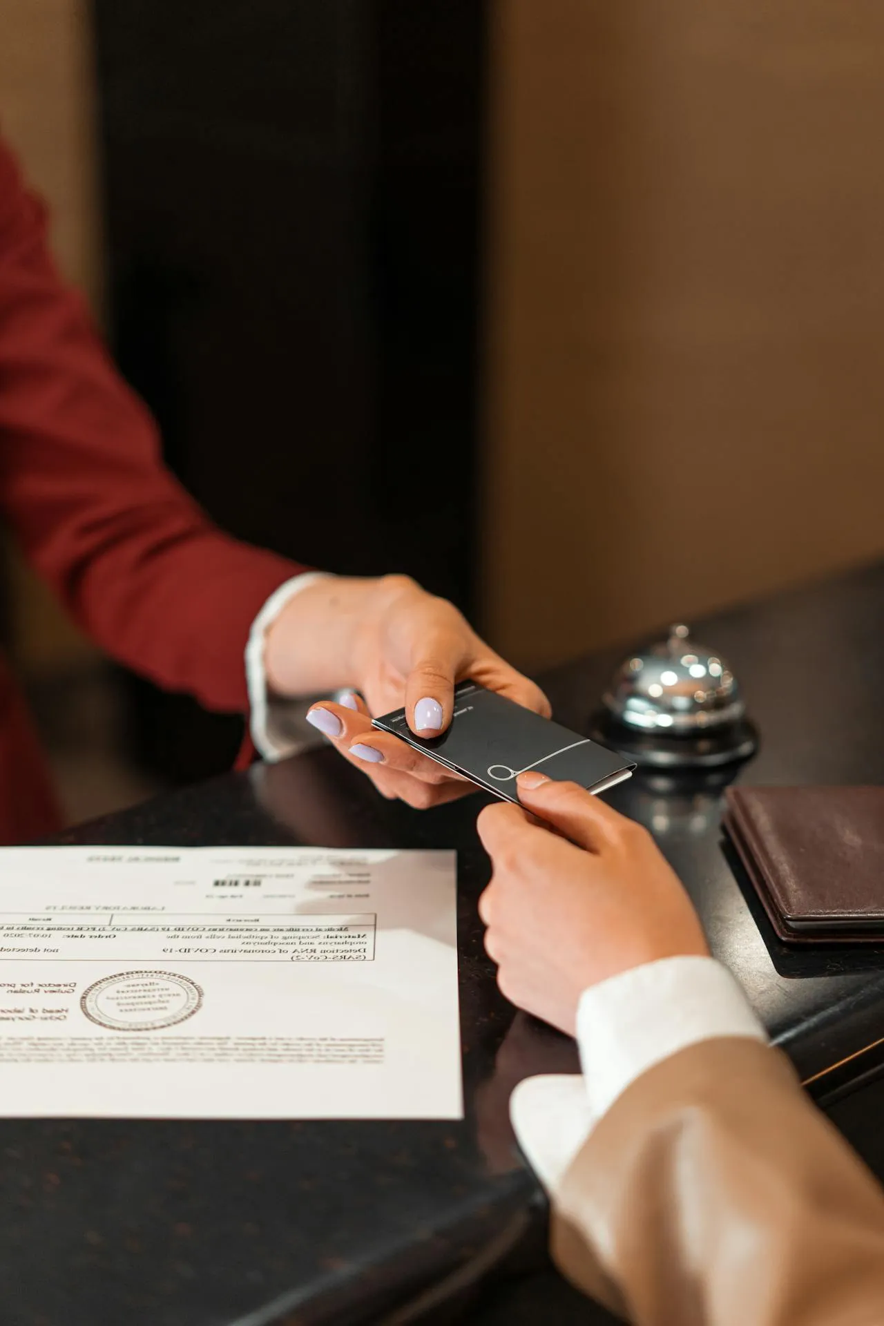 Hände reichen Kreditkarte am Hotelrezeption mit Dokument und Glocke