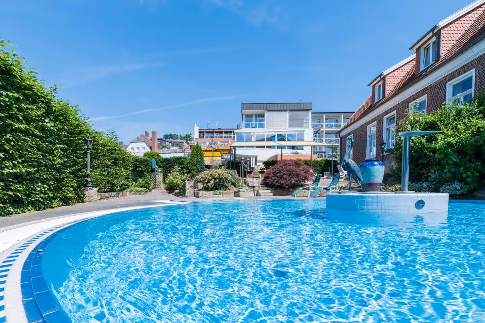 Blauer Swimmingpool mit Garten und modernen Gebäuden im Hintergrund