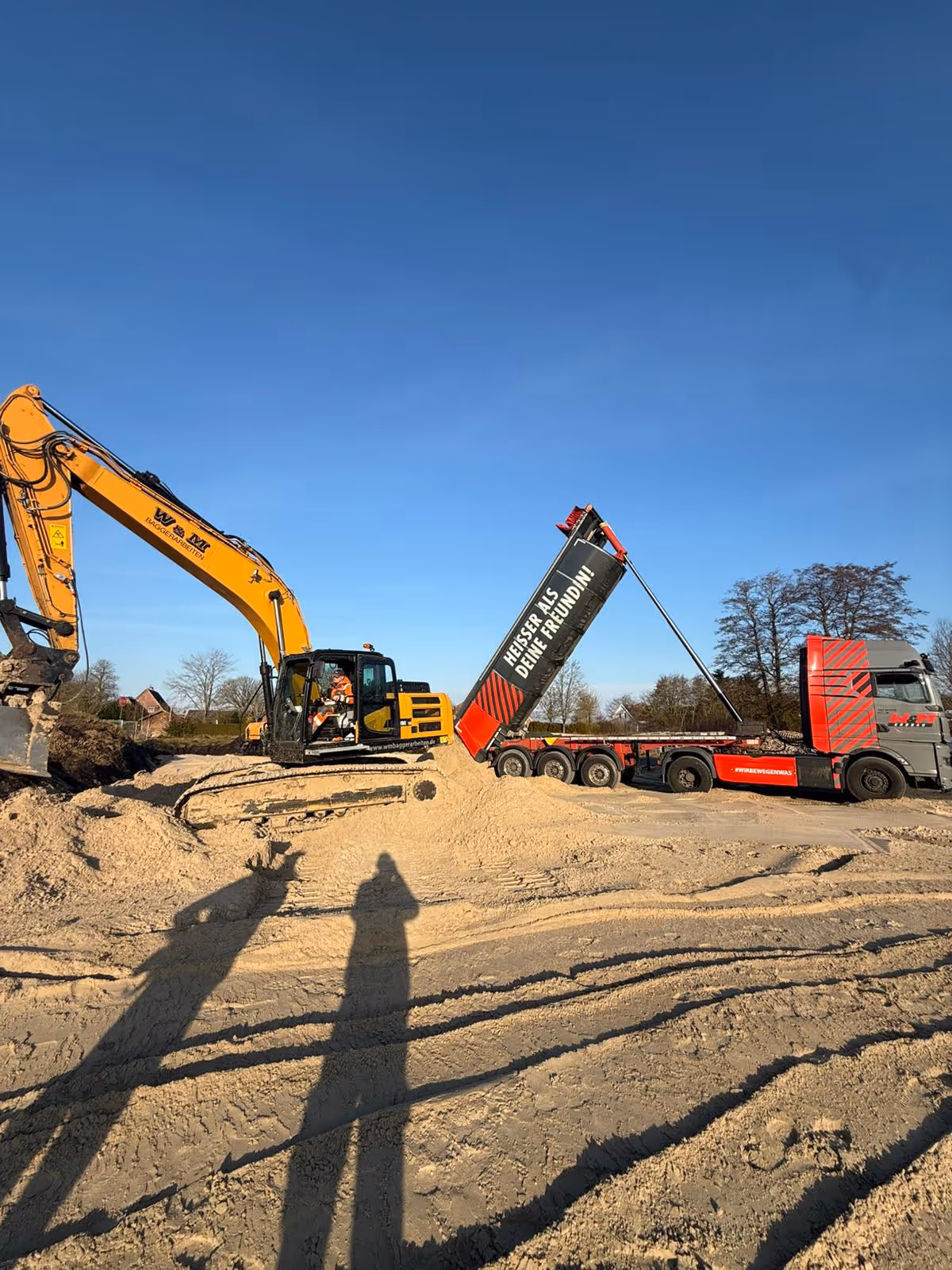 Bagger und LKW bei Tiefbauarbeiten für Hausbau