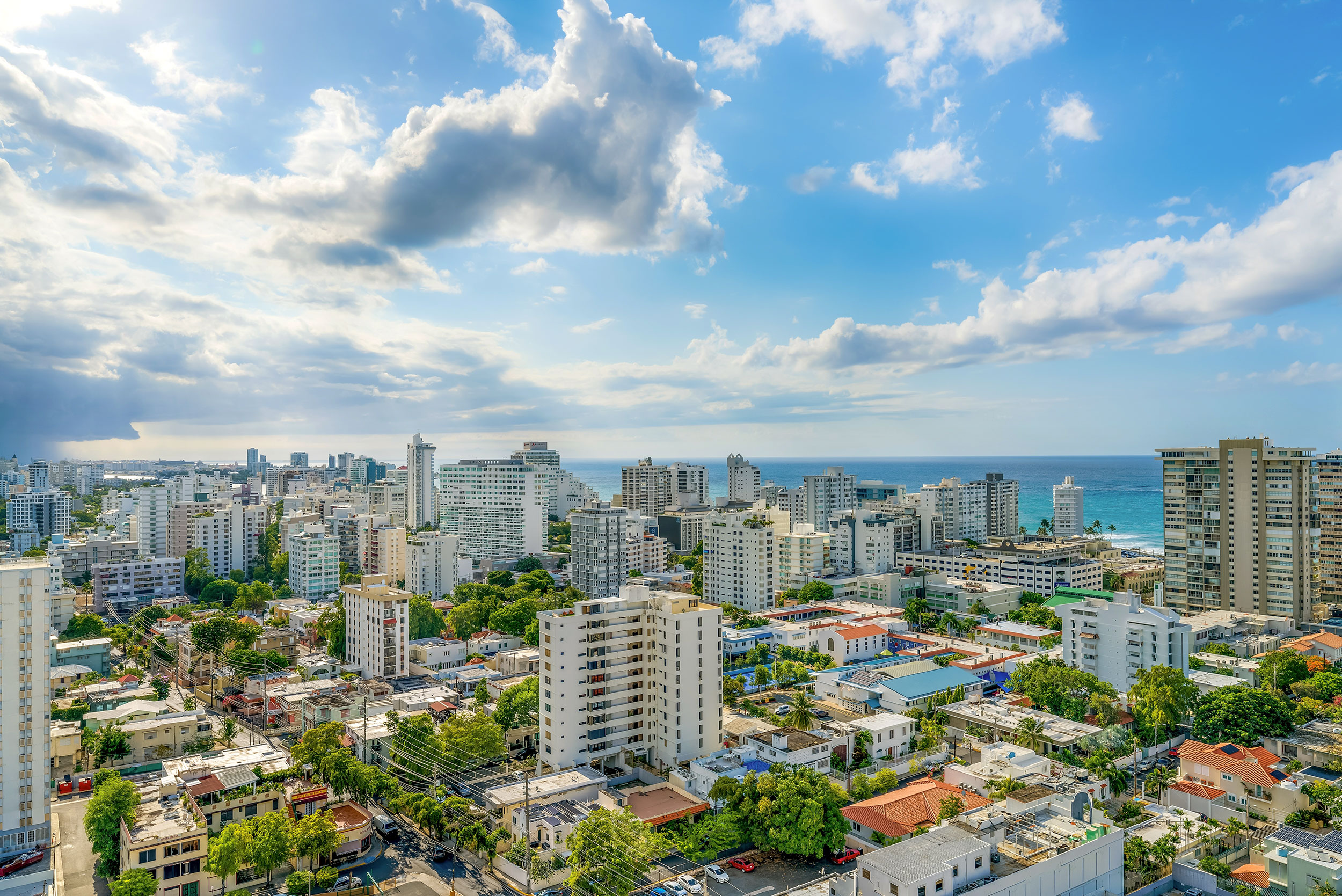 Condado cityscape in Puerto Rico with high-rise buildings near the ocean under a partly cloudy blue sky.