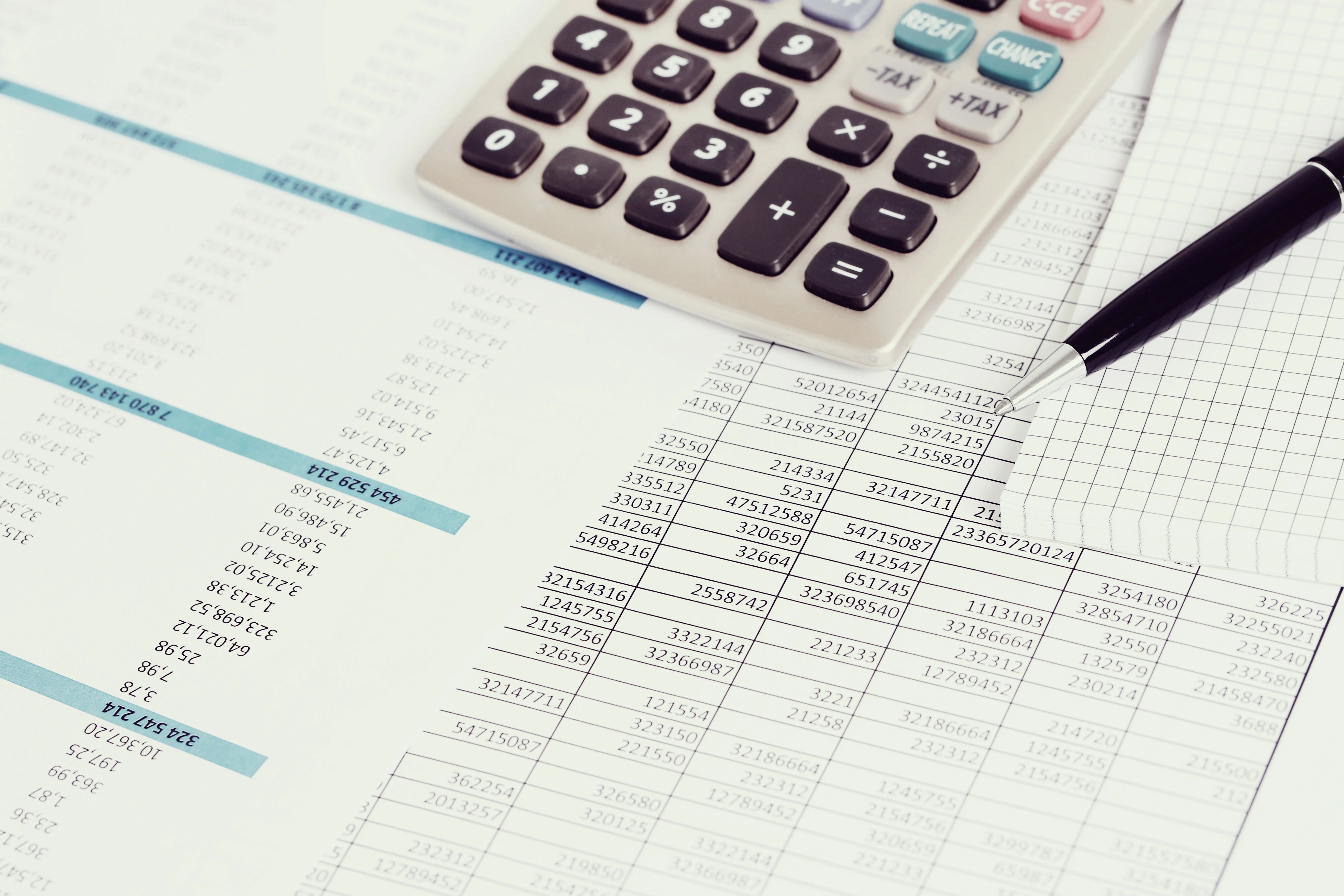 Un fichier Excel est imprimé sur des feuilles de papier. Une calculatrice est posée dessus.