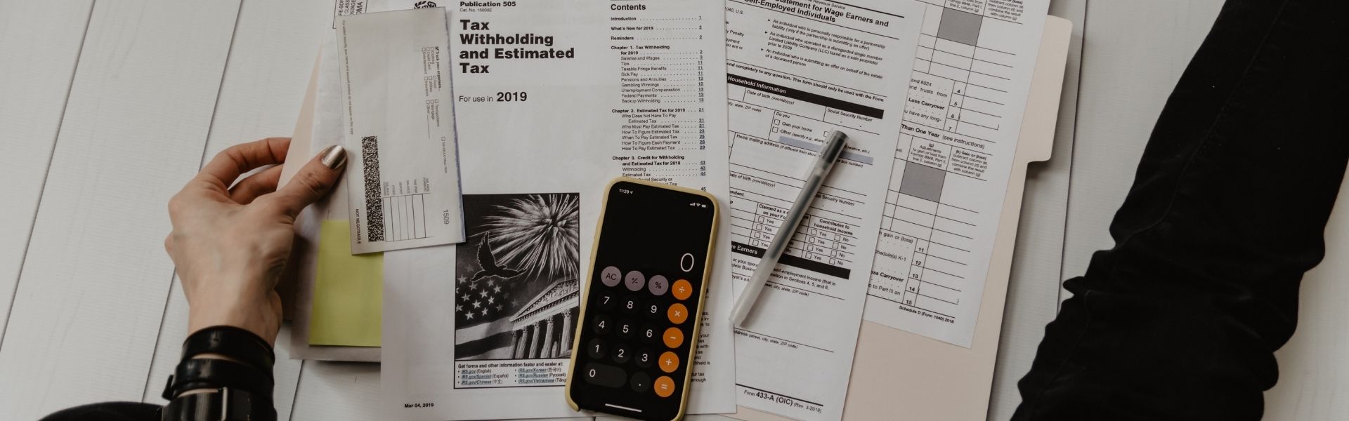 image illustrant plusieurs factures disposées sur une surface, à côté d'un téléphone portable sur lequel s'affiche une calculatrice