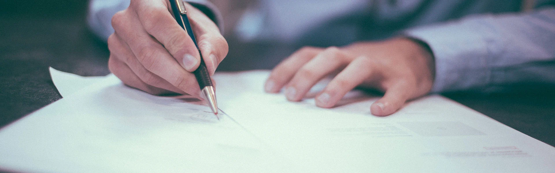 image illustrant les mains d'un dirigeant tenant un stylo, en train de rédiger sur des feuilles de papier