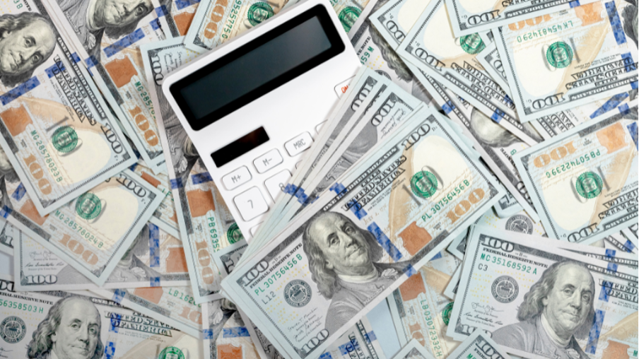 Image illustrant le flux de trésorerie. Une calculatrice posée au milieu de plusieurs billets de dollars.