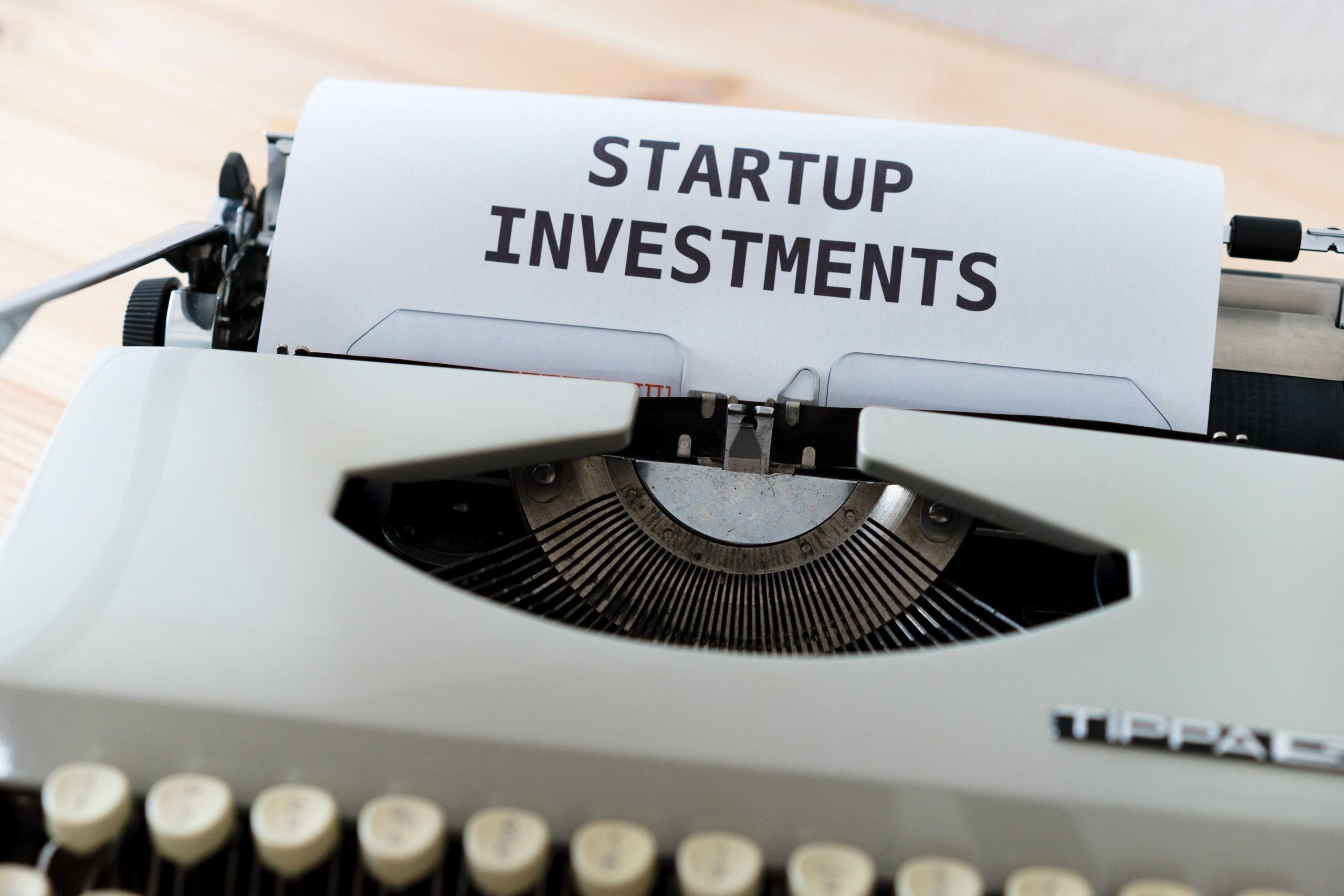 Gros plan sur une machine à écrire. Sur la feuille dans le rouleau il est écrit "startup investments"