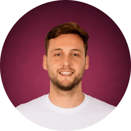 Homme souriant avec barbe légère et t-shirt blanc sur fond violet.