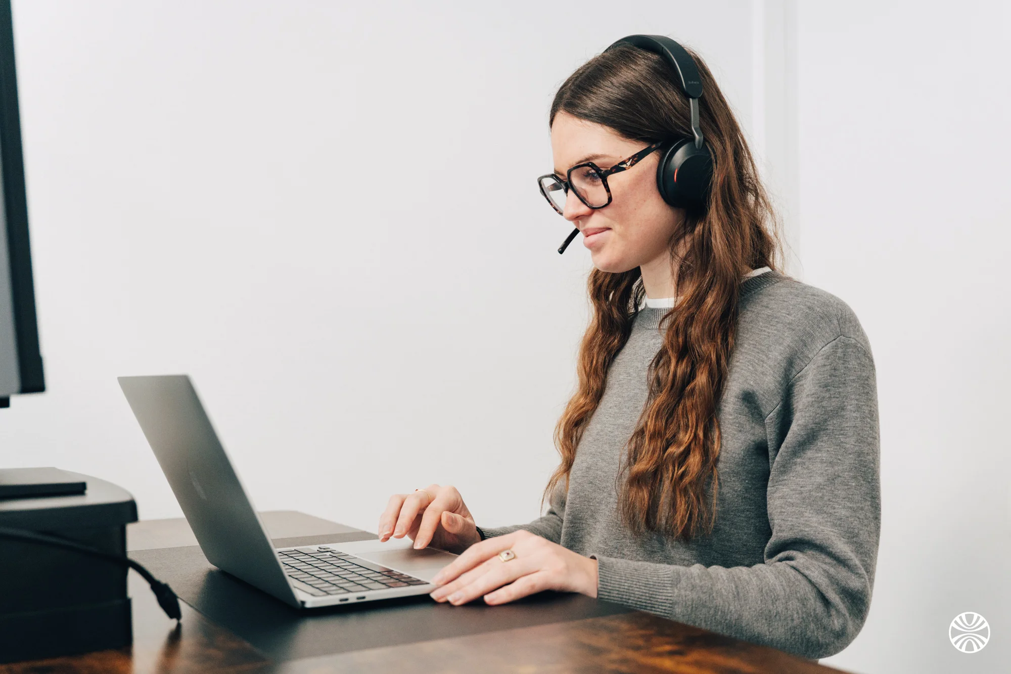 Femme portant un casque avec microphone travaillant sur un ordinateur portable à une table.
