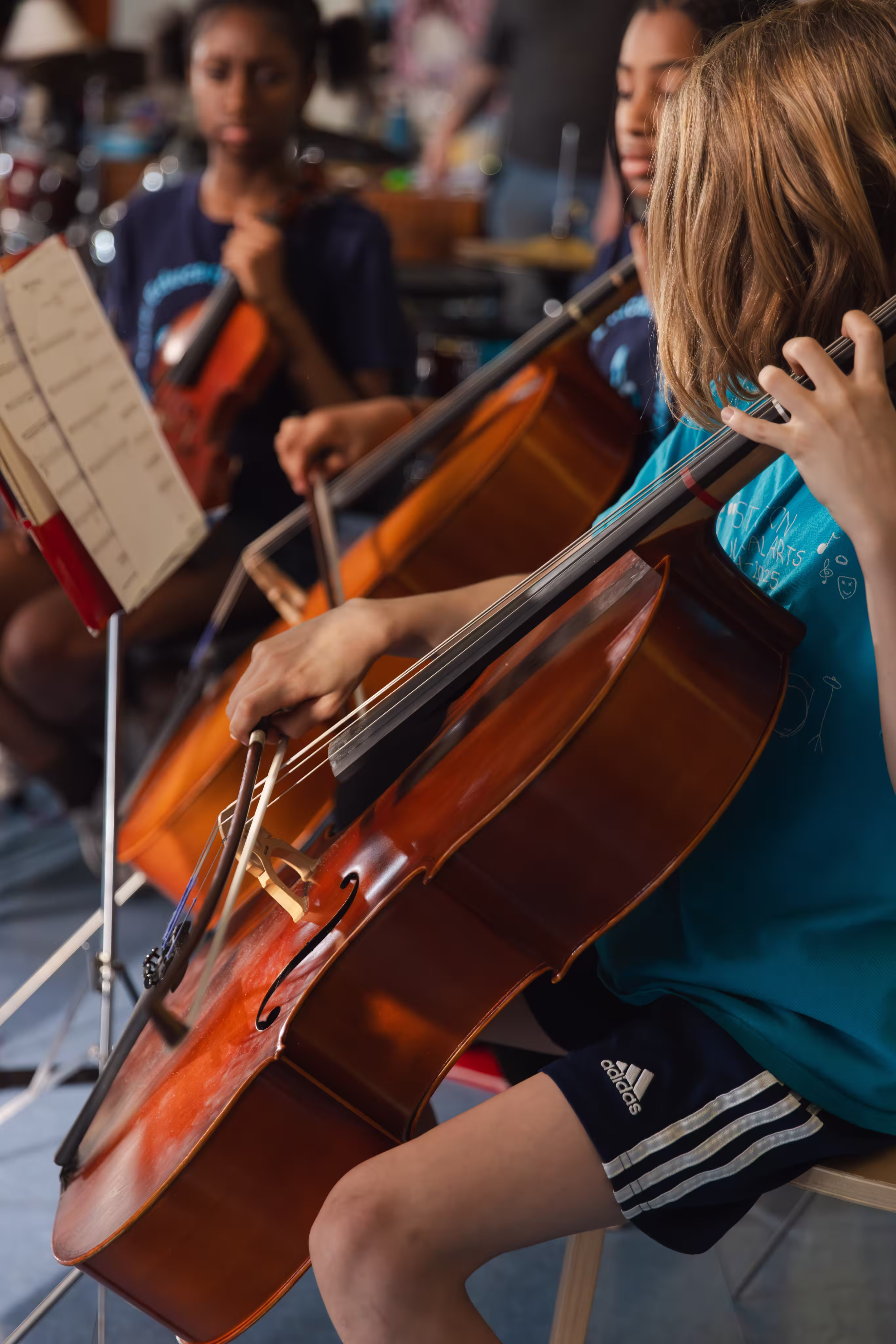 Young musicians playing cello and violin during a rehearsal or class.