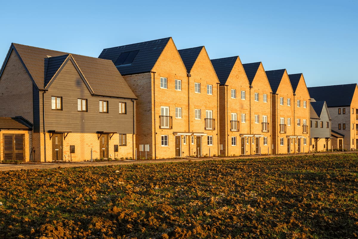 Newly built modern row houses with brick and dark siding under a clear blue sky at sunset.