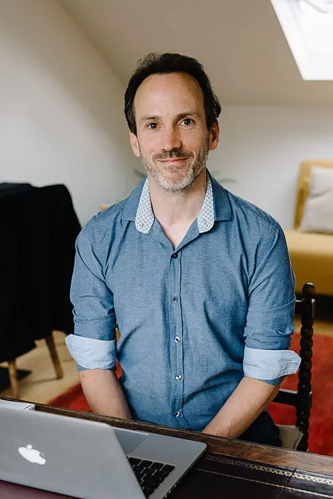 Timothy Malnick sitting at his laptop in his home office
