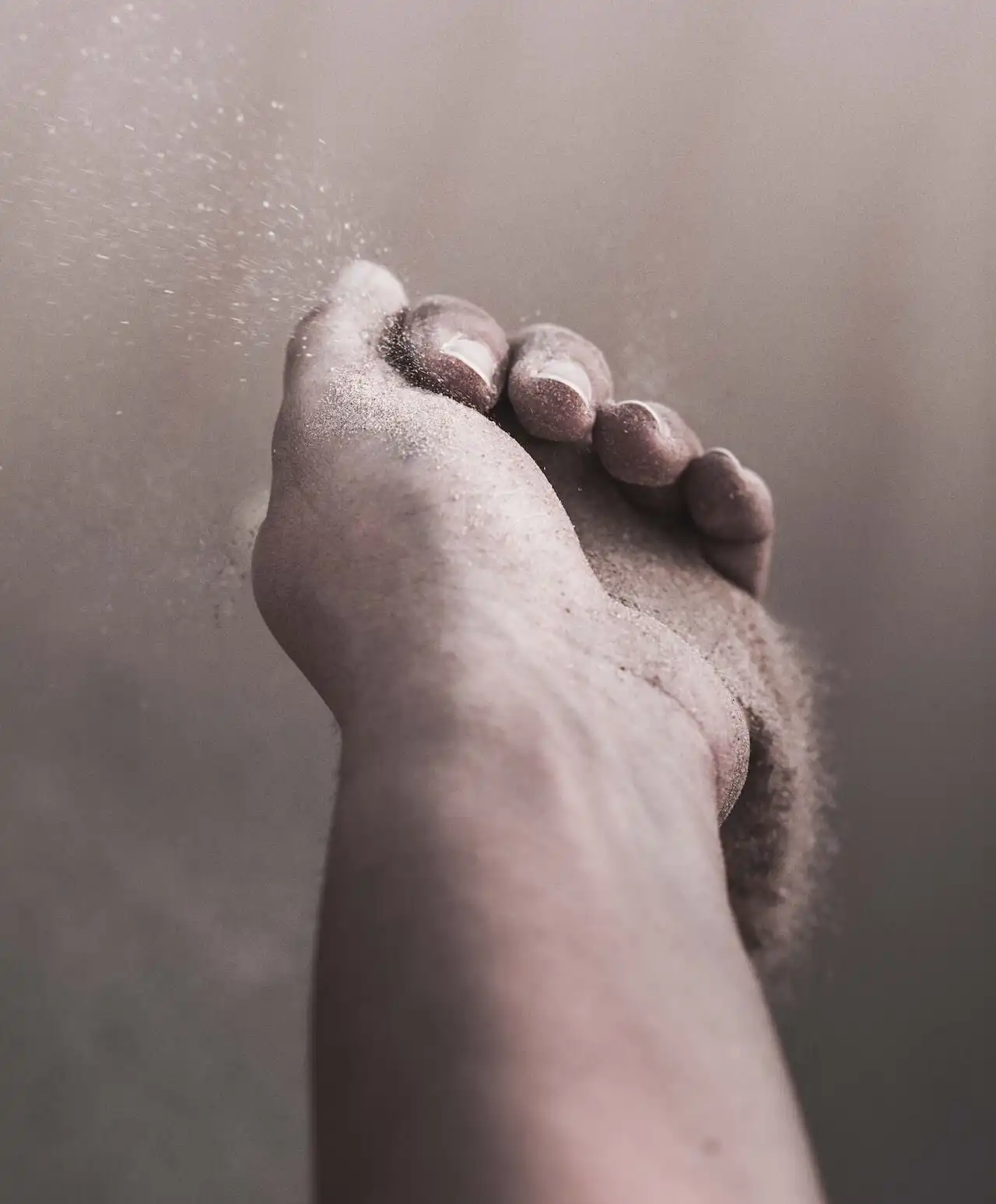Close-up of a hand letting sand slip through its fingers, symbolising the impermanence of control and the importance of letting go