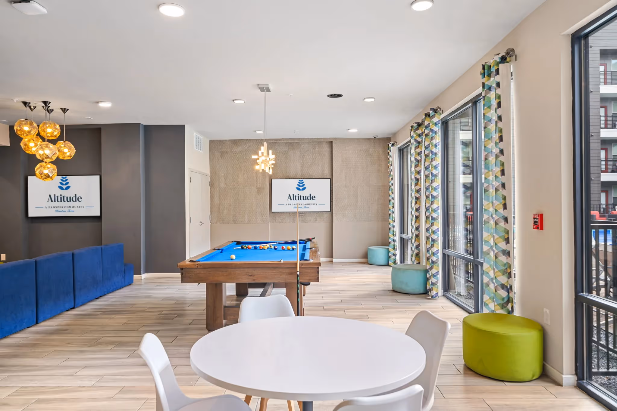 Vibrant resident lounge with a billiards table, comfortable seating, and large windows, perfect for socializing at Altitude in Houston, TX.