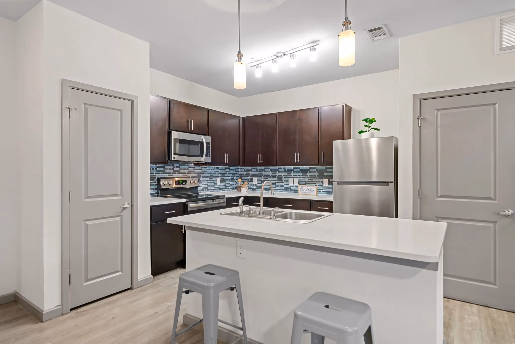 Spacious apartment kitchen with dark cabinetry, stainless steel appliances, a breakfast bar, and modern lighting at Altitude in Houston, TX.