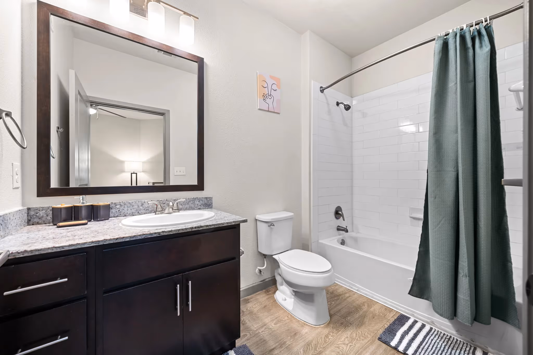 Contemporary bathroom with a dark wood vanity, white subway tile shower, and a large mirror, in an apartment at Altitude in Houston, TX.