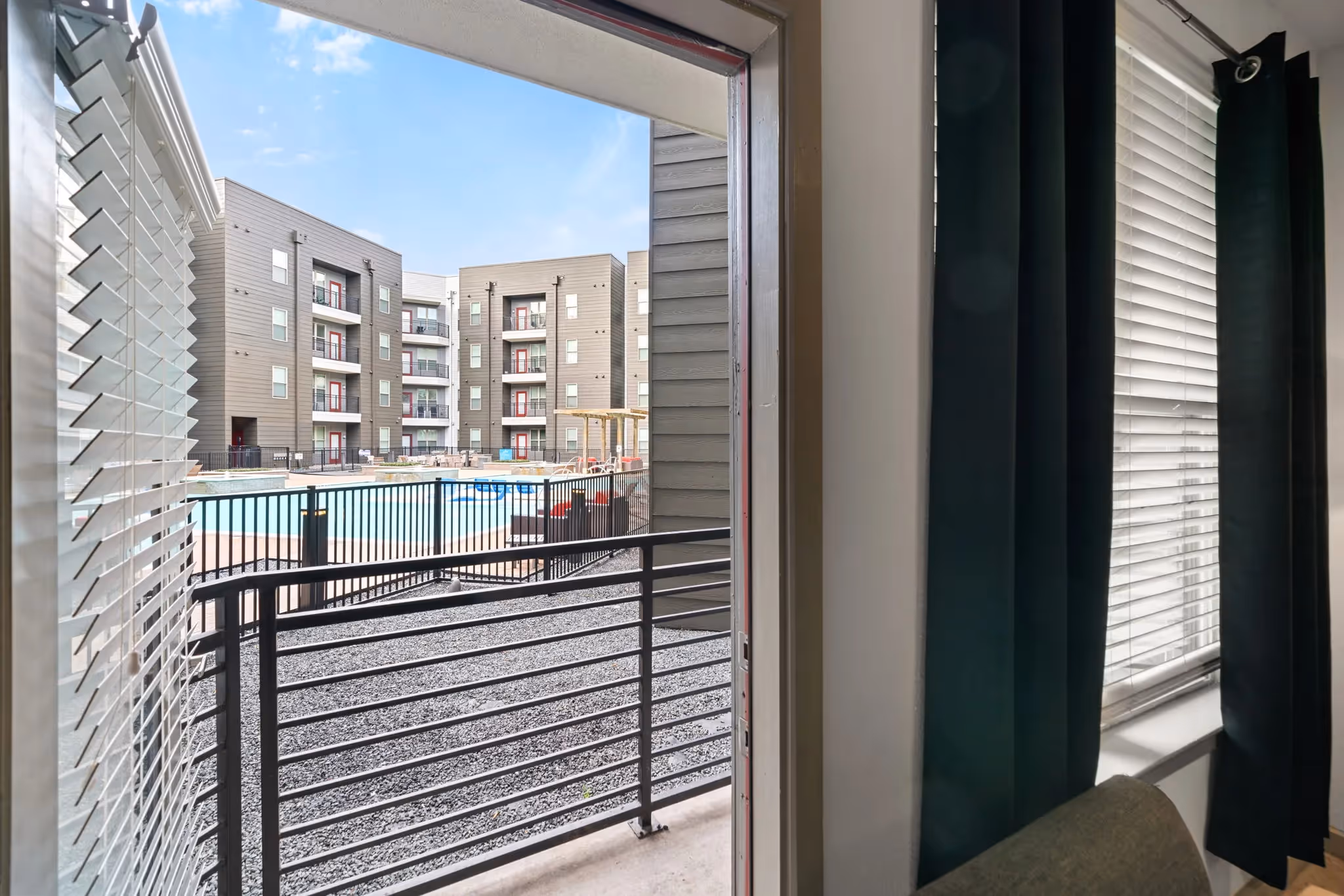 View of the community swimming pool and courtyard from a private balcony, offering outdoor living at Altitude apartments in Houston, TX.