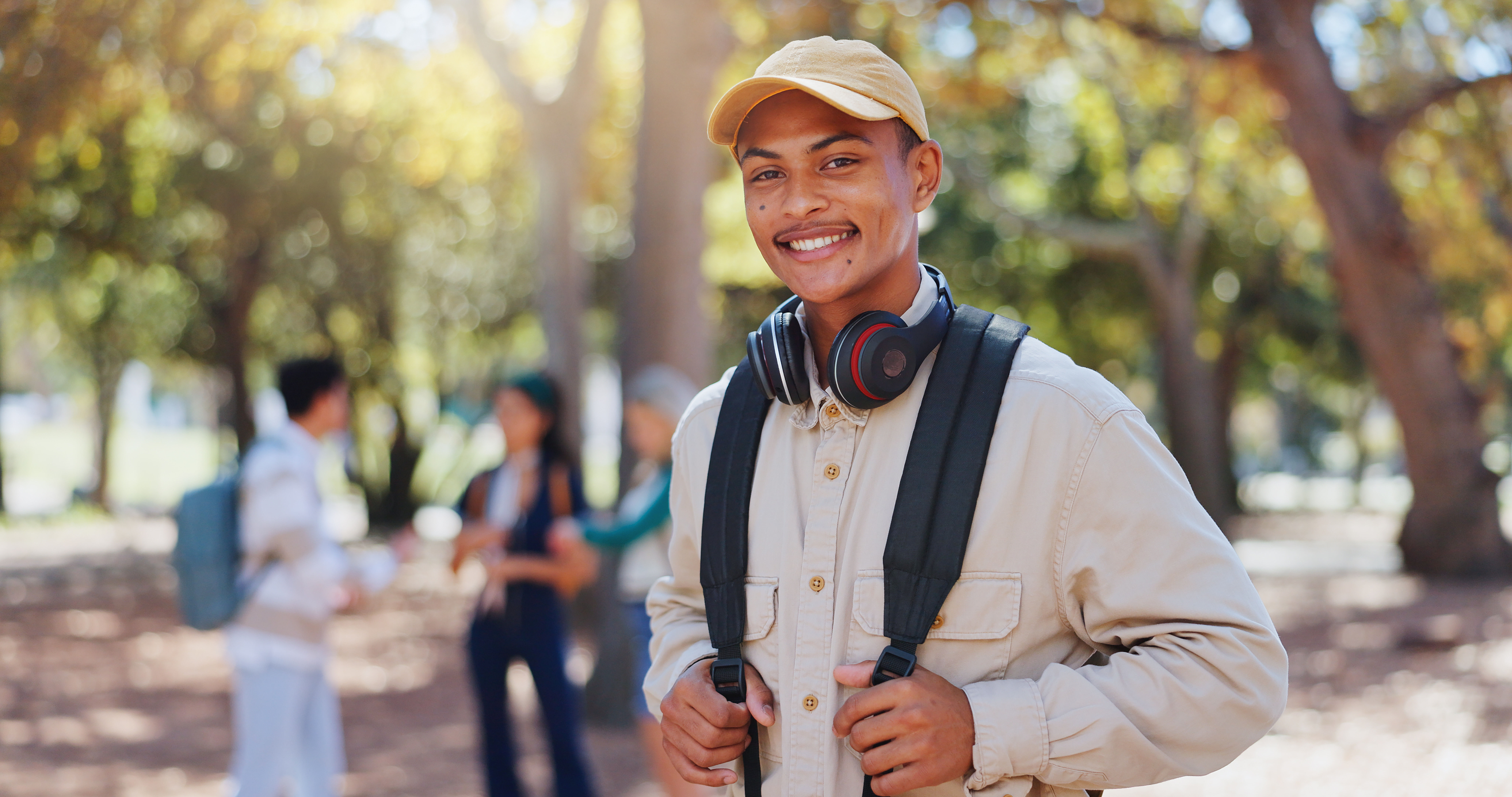 Guy with book sack standing outside near tree stock image