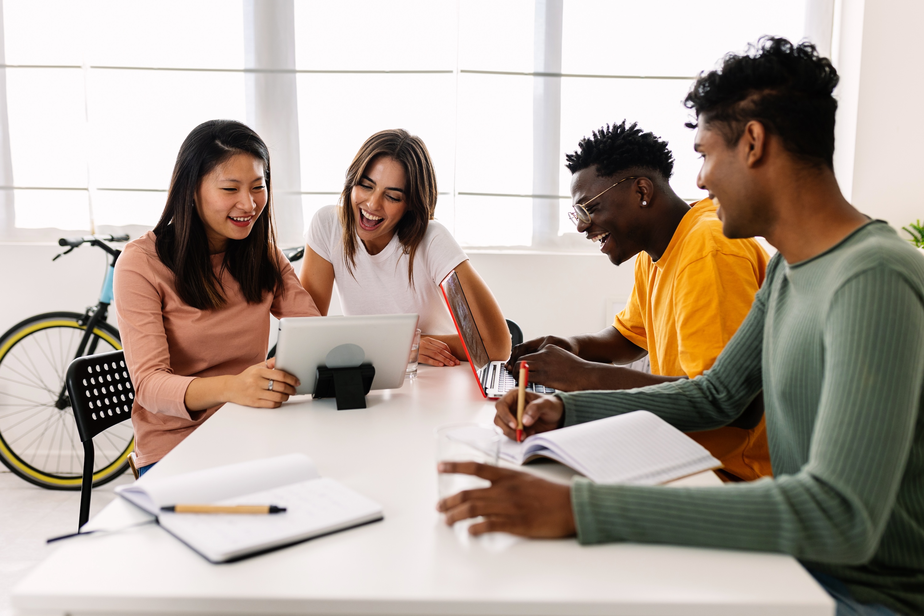A group of people collaborating with a tablet and laptops in a bright, modern community room at Altitude.