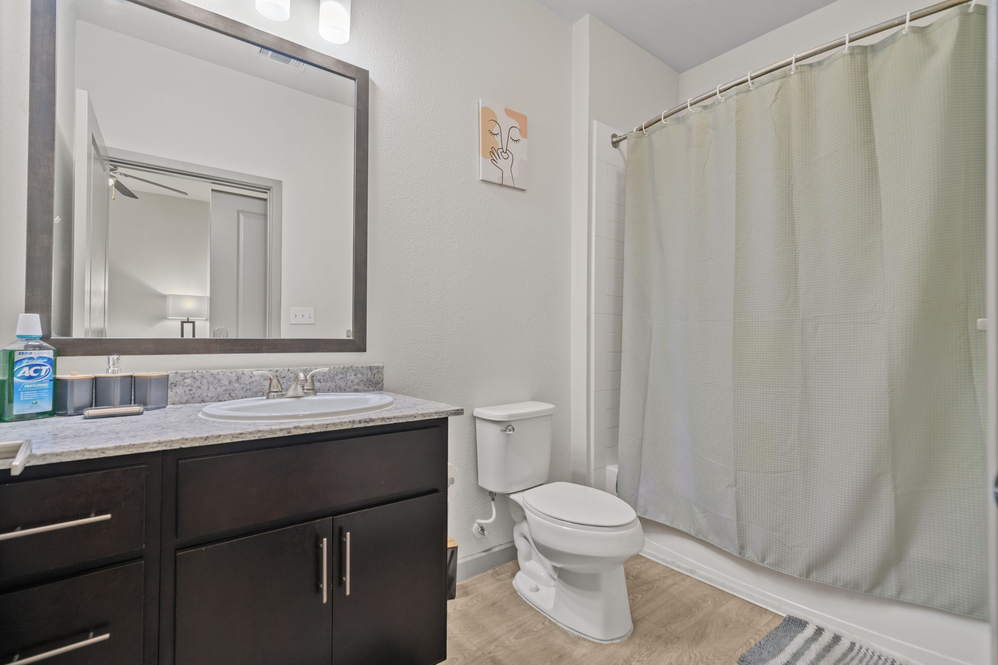 Contemporary bathroom with a dark wood vanity, white subway tile shower, and a large mirror, in an apartment at Altitude in Houston, TX.