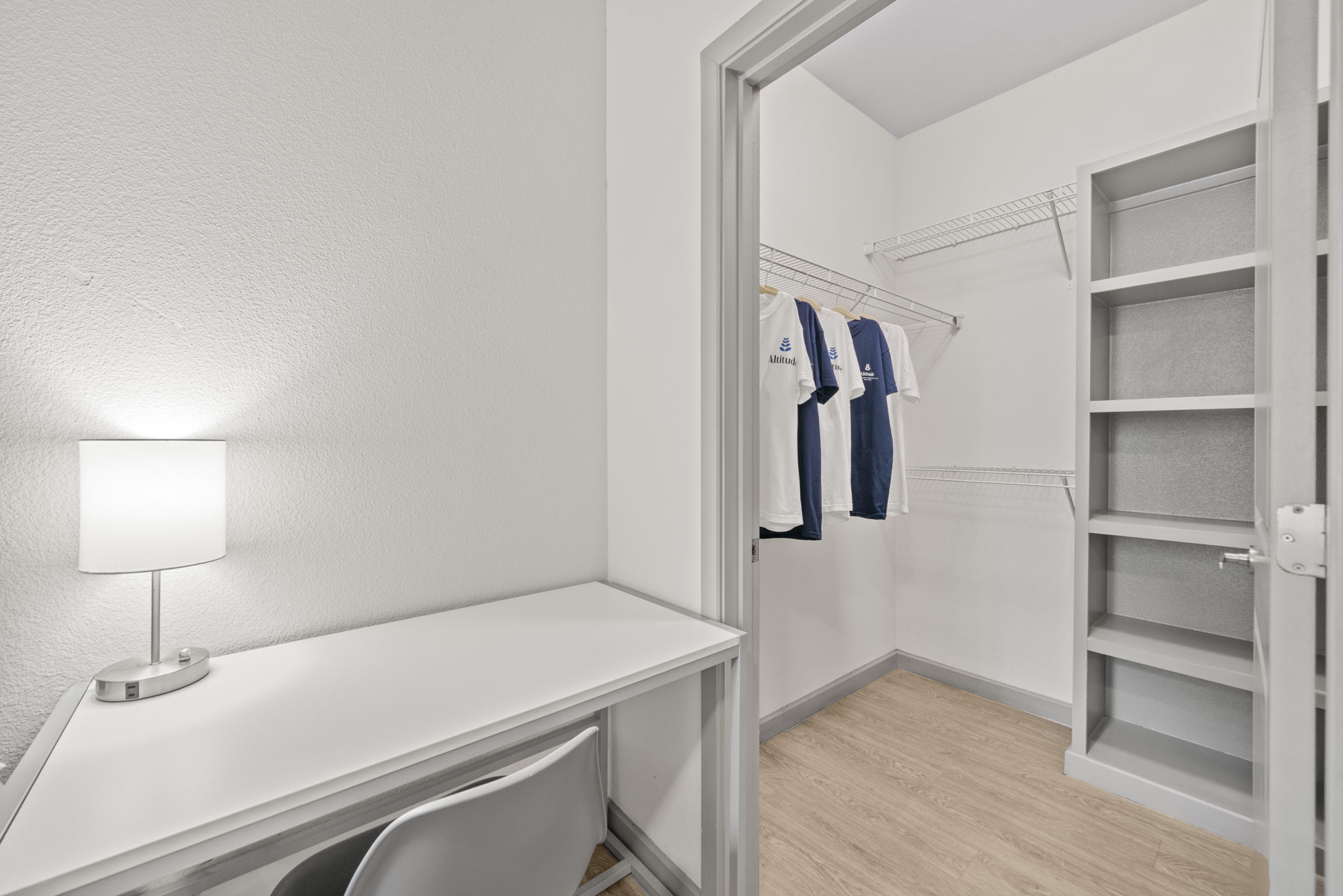 Spacious walk-in closet with built-in shelves and drawers, featuring an Altitude branded t-shirt, in an apartment at Altitude in Houston, TX.