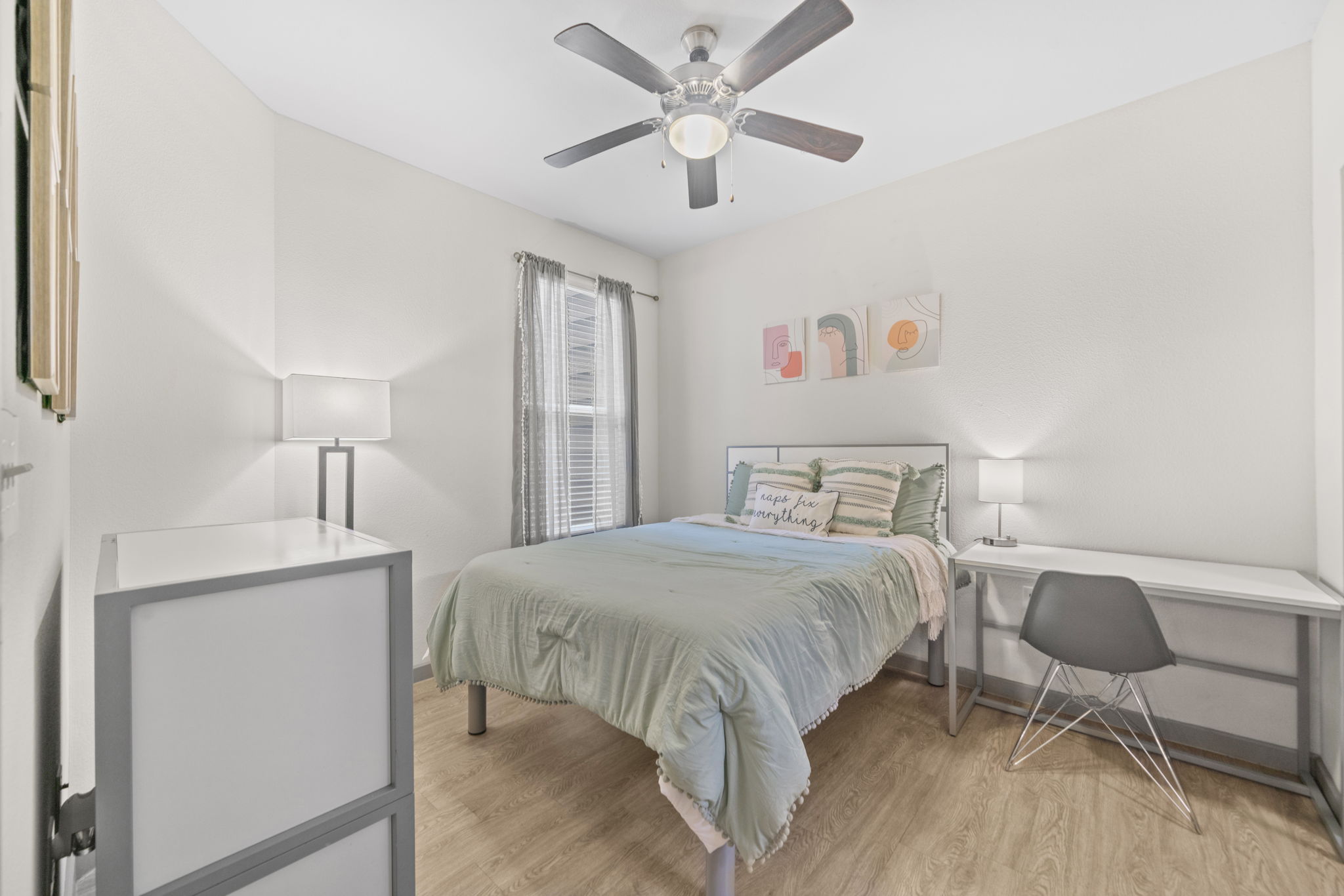 Bright bedroom with a modern bed, a desk for studying, and light green bedding in an apartment at Altitude in Houston, TX.