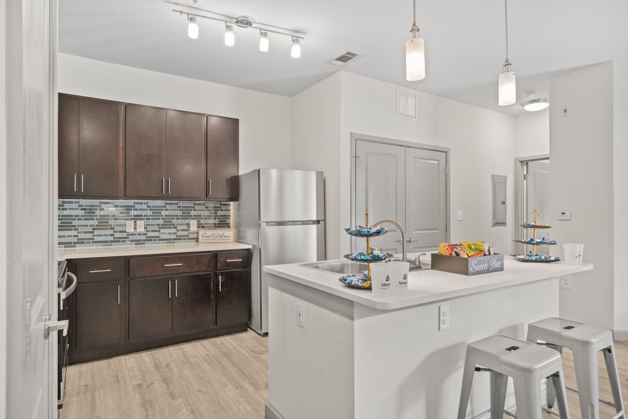 Spacious apartment kitchen with dark cabinetry, stainless steel appliances, a breakfast bar, and modern lighting at Altitude in Houston, TX.