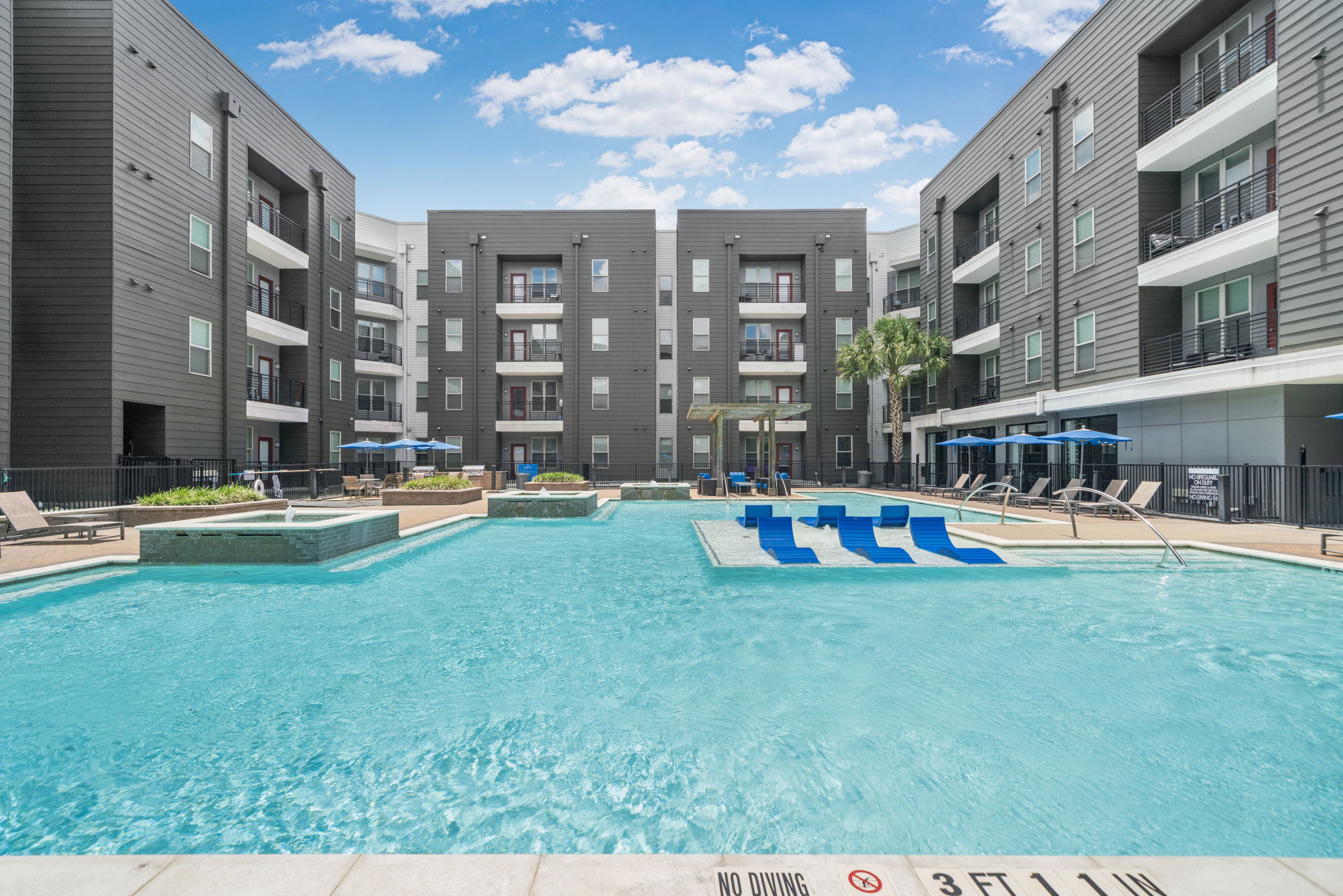 Spacious outdoor swimming pool and social area with lounge chairs and water features, part of the amenities at Altitude in Houston, TX.