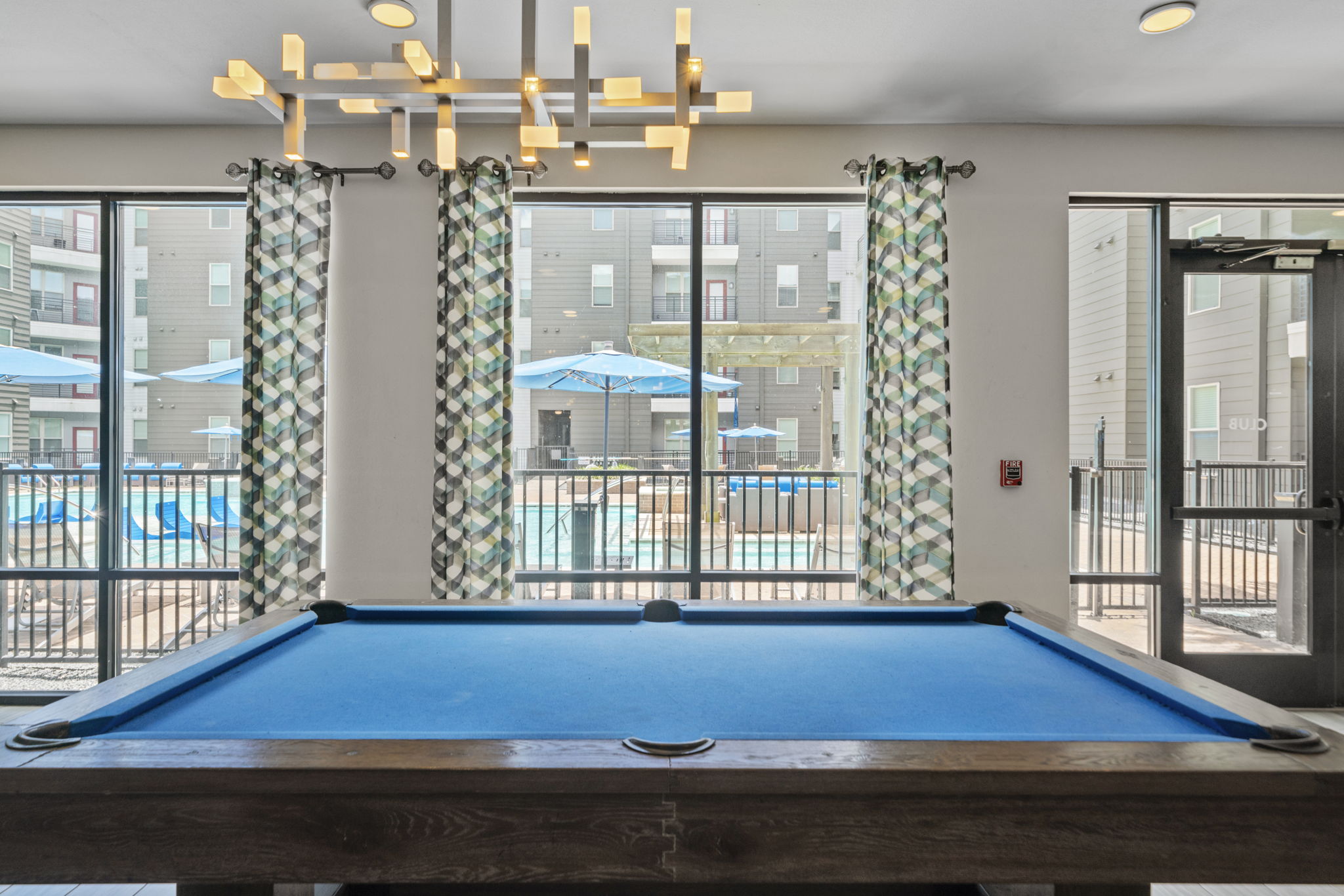Vibrant resident lounge and game room with a billiards table and modern furniture, offering a social space at Altitude in Houston, TX.