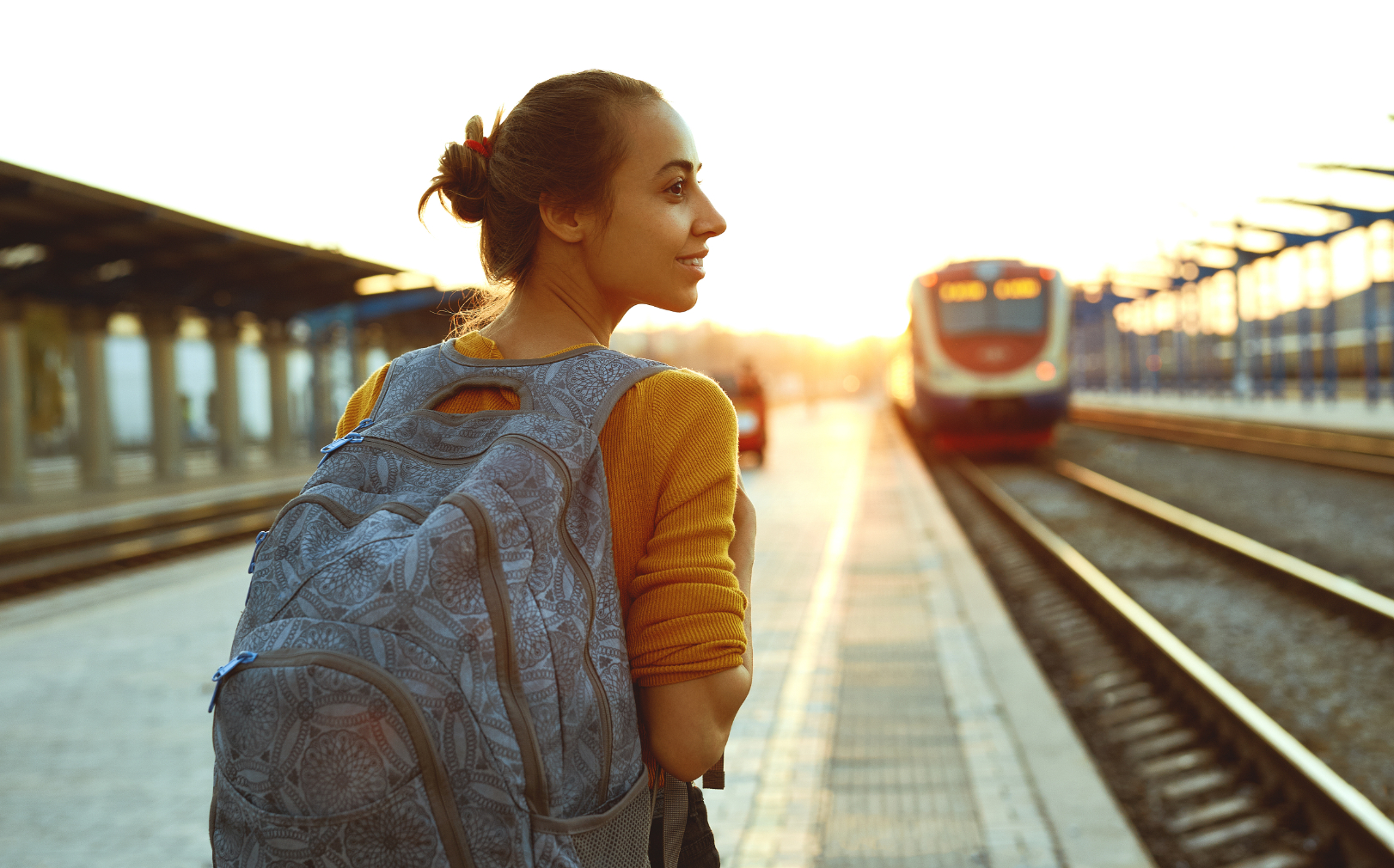 Girl with book bag next to train