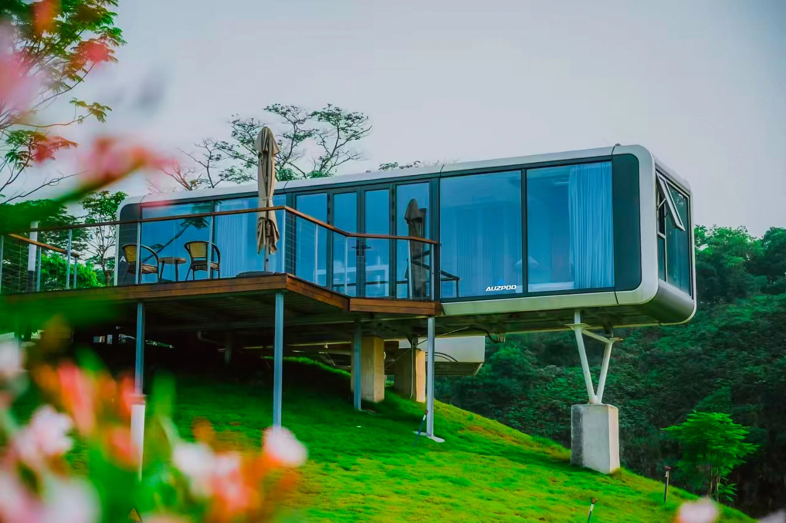 The exterior of a completed Auzpod modular pod home, elevated on stilts among trees