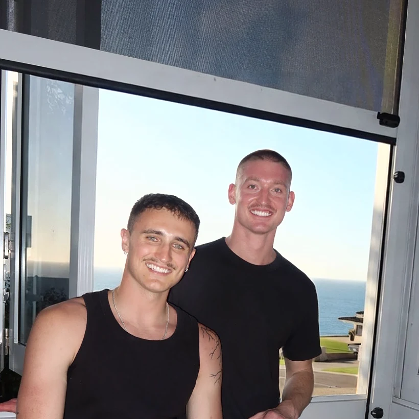 Enkindle Group founders Harvie Williams and Kobi Martin by a window overlooking the ocean in Perth