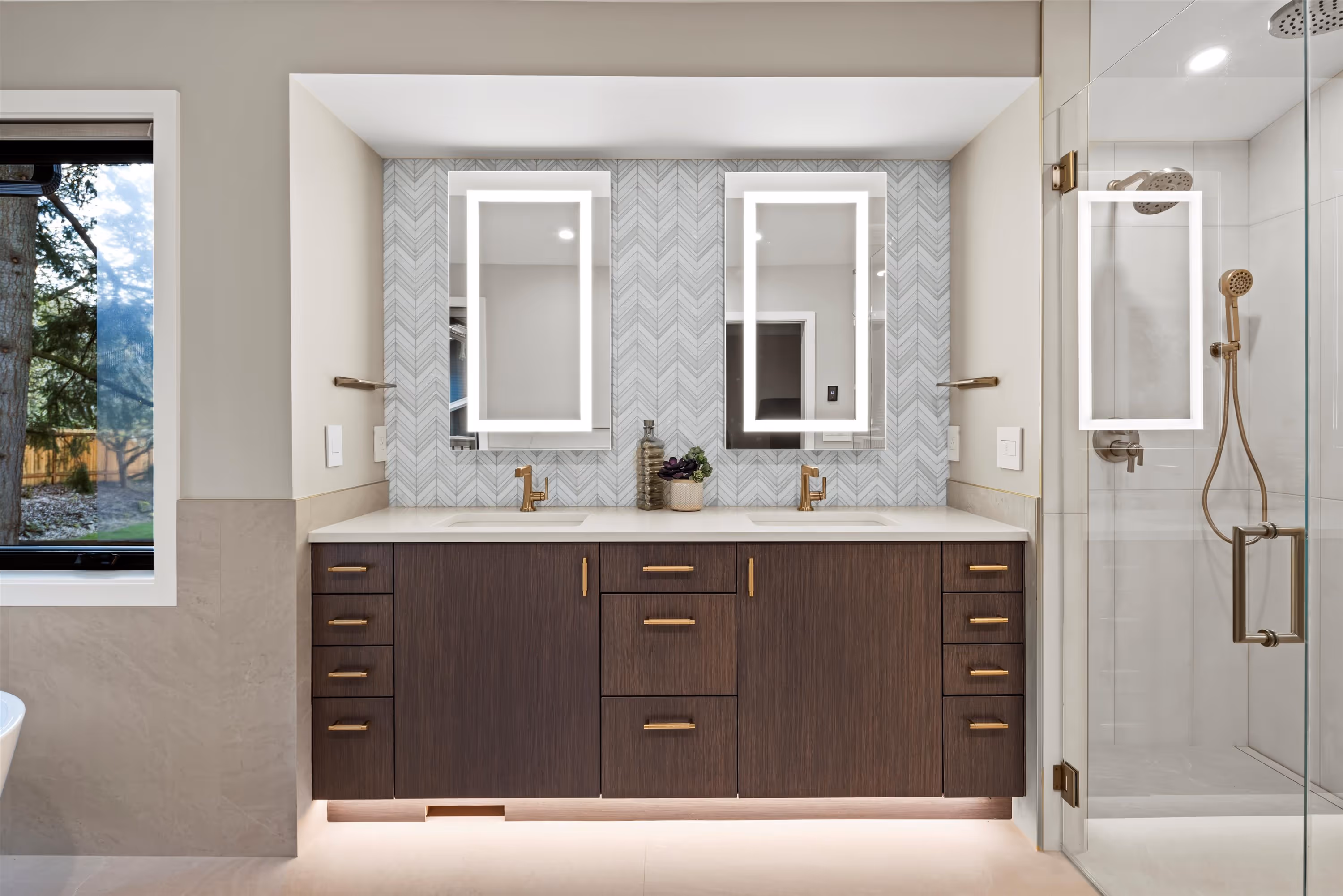 Modern bathroom with double sink vanity, illuminated mirrors, decorative backsplash, and glass shower.