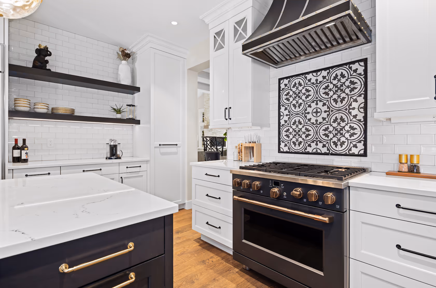 Modern kitchen with black and gold stove, white cabinets, subway tiles, and patterned tile backsplash.