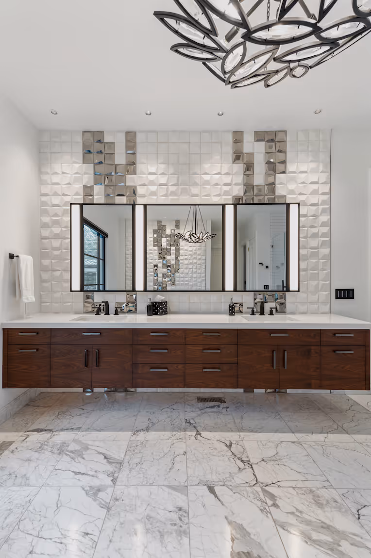 Modern bathroom with floating dark wood vanity, double sinks, illuminated mirrors, and marble tile floor.