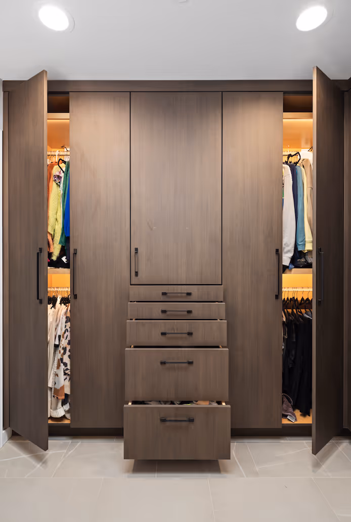 Modern wooden wardrobe with open side doors showing hanging clothes and five central drawers.