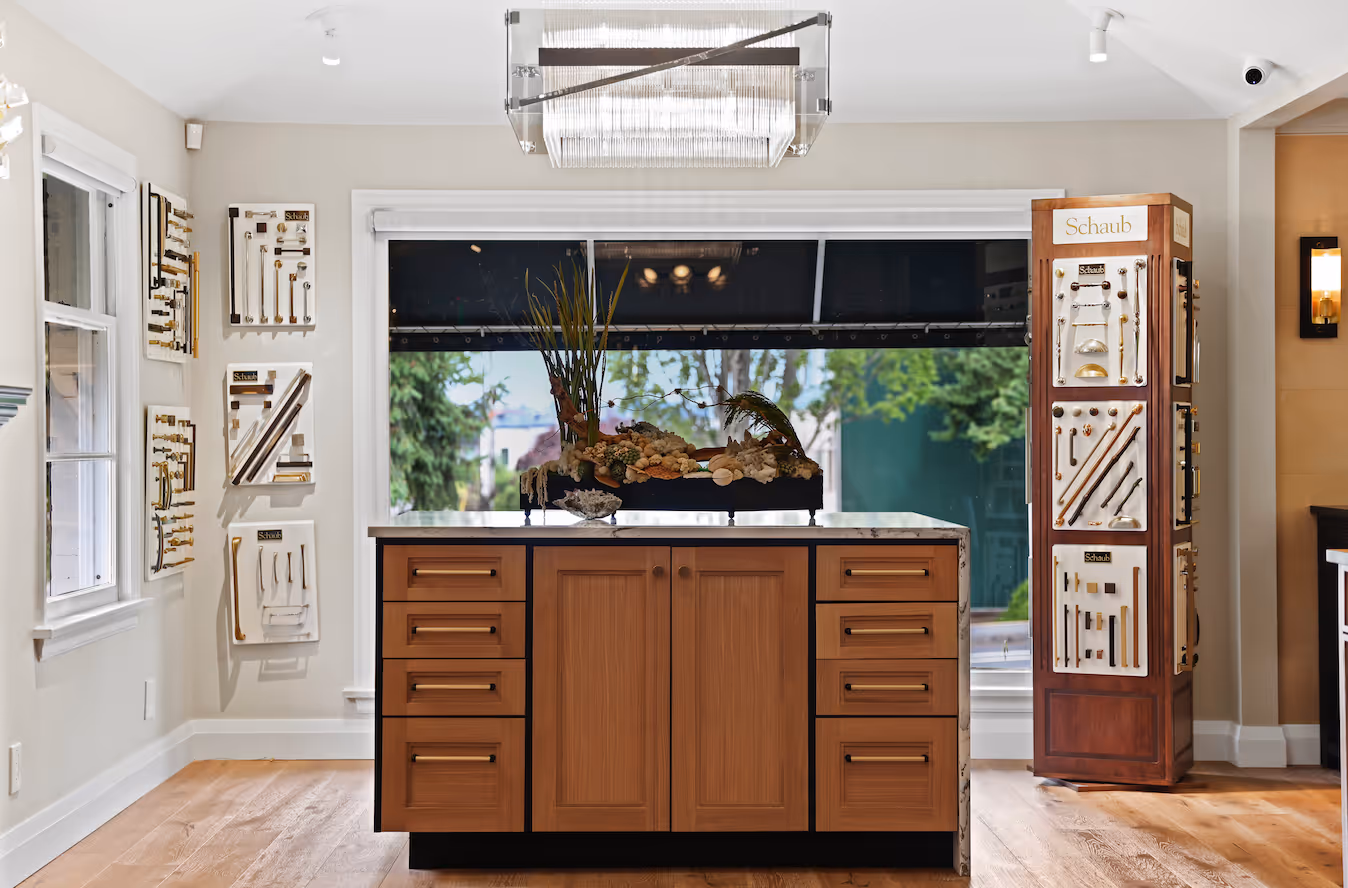 Showroom with wood cabinet island and displays of various cabinet handles on walls and a pillar.