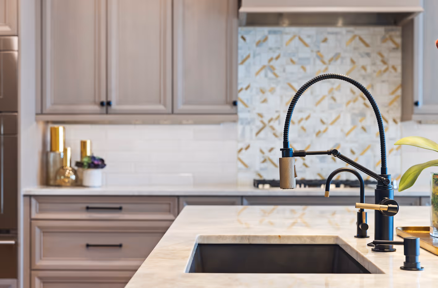 Modern kitchen sink with a black spring coil faucet and beige marble countertop.