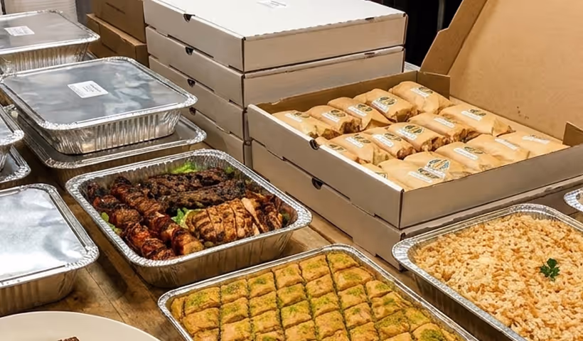 Catering trays with sandwiches, rice, meat, fresh salads and baklava